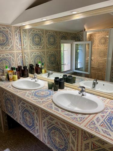 La salle de bains est pourvue de 3 lavabos et d'un grand miroir. dans l'établissement Villa des Roses, à Roussillon
