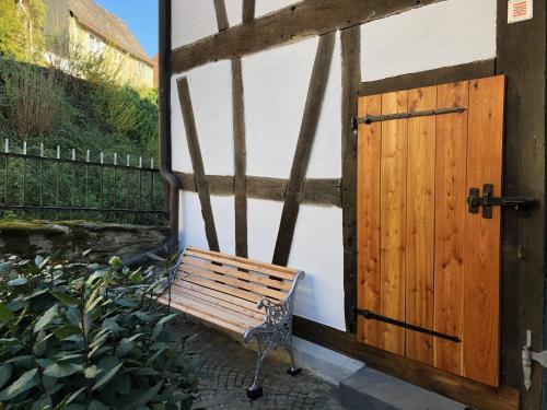 a wooden door and a bench next to a building at Gut Bunt Ferienhaus in Runkel