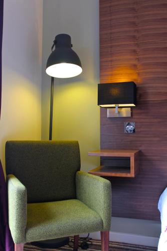 a living room with a green chair and a lamp at Highfield Hotel in Houghton le Spring