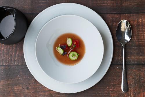 a white plate with a bowl of soup and a spoon at Gasthof Mühle in Aesch