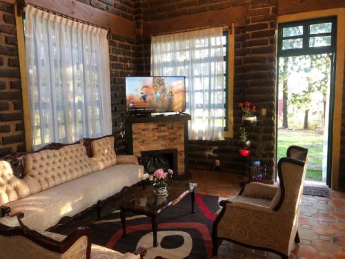 sala de estar con sofá y chimenea en Hermosa Cabaña en la Naturaleza, en Huitzilac