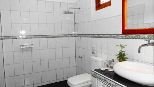 a white bathroom with a toilet and a sink at Regina Beach Bungalow in Trincomalee