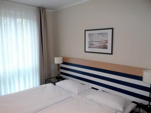 ツィングストにあるMöwe App 510のベッドルーム1室(青と白のストライプのヘッドボード付きのベッド1台付)