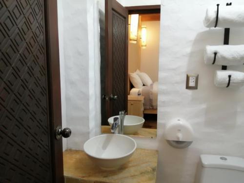 a bathroom with a sink and a toilet and a mirror at Hotel Na´Lum in San Cristóbal de Las Casas