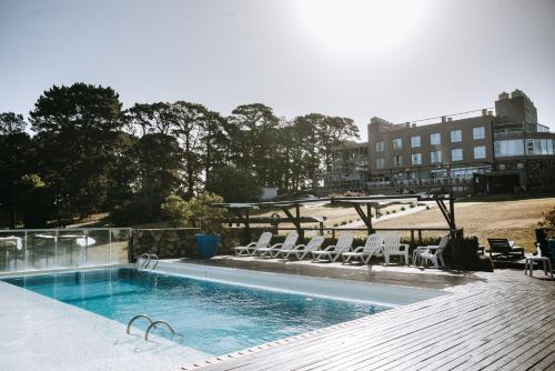 una piscina con sillas, una mesa y un edificio en Posta Natural en Tandil