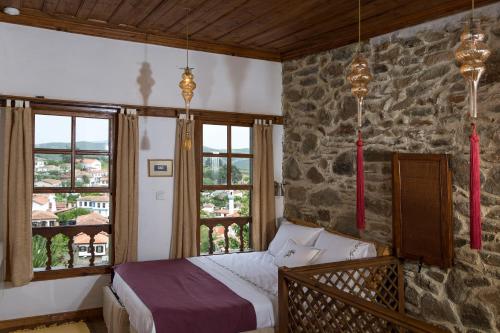 ein Schlafzimmer mit einem Bett und einer Steinmauer in der Unterkunft Terrace Houses Sirince in Selçuk