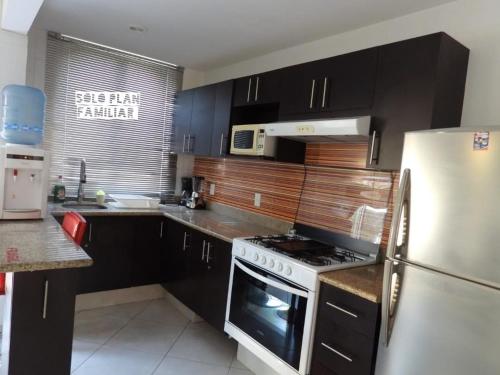 a kitchen with black cabinets and a white refrigerator at Residencial Club Nautico Teques in Tequesquitengo