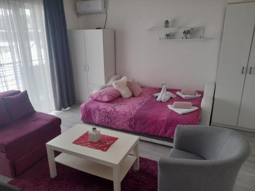 a bedroom with a bed and a chair and a table at Family Apartmani Le in Leskovac