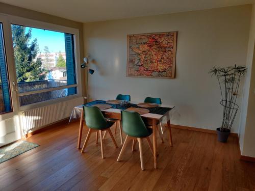 une salle à manger avec une table et des chaises vertes dans l'établissement Appartement du parc des thermes, à Thonon-les-Bains