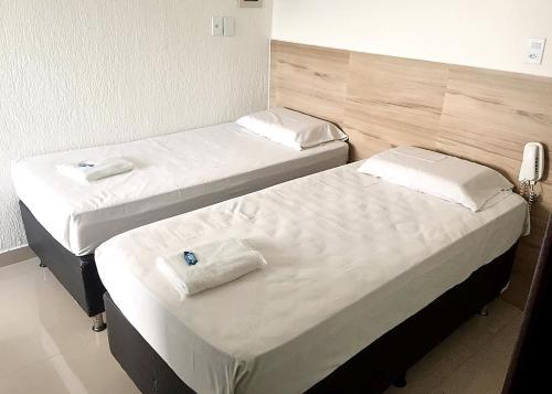 two beds in a room with white sheets and towels at Hotel Premier in Brasilia