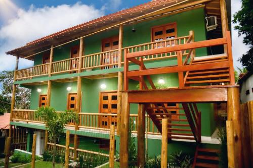 a green house with a large deck on it at Encanto do Mar Pousada in Caraíva