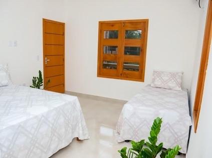 una camera con due letti, un comò e uno specchio di Encanto do mar residencial a Caraíva