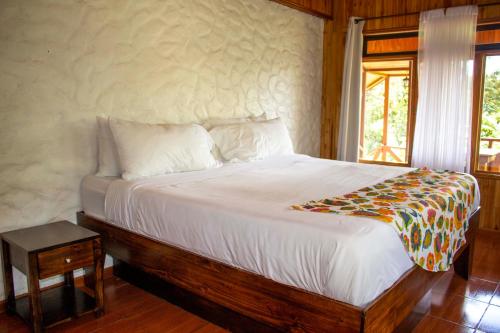 ein Schlafzimmer mit einem großen Bett mit weißer Bettwäsche und einem Fenster in der Unterkunft Hotel Holístico Monteverde in Monteverde Costa Rica