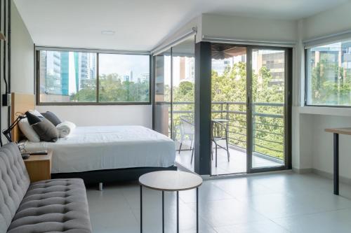 a bedroom with a bed and a couch and windows at Hotel Bambu Milla De Oro in Medellín