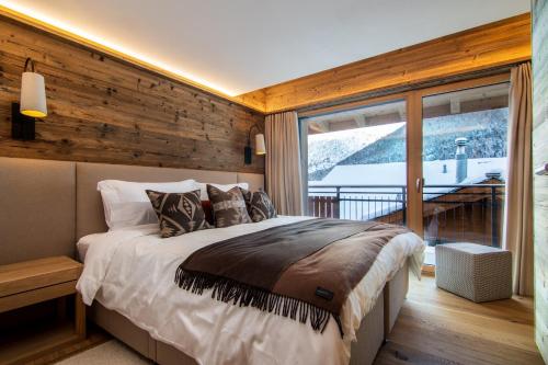 a bedroom with a bed and a large window at Berghof Penthouse in Saas-Fee