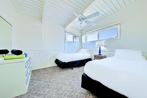 een witte kamer met 2 bedden en een raam bij Seascape Homes in Newport Beach