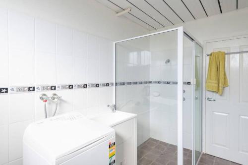 a white bathroom with a shower and a sink at Dreamtime Beach Retreat in Forster
