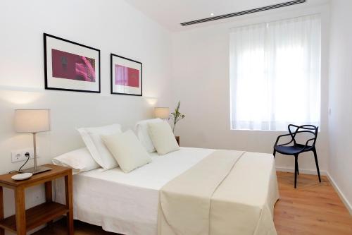 a white bedroom with a white bed and a chair at Aspasios Rambla Catalunya Apartments in Barcelona