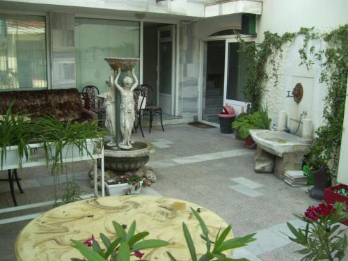a patio with a statue and a table and some plants at Family Hotel George in Svilengrad
