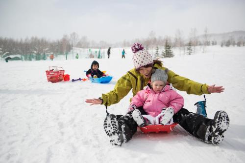 a woman pulling a child on a sled in the snow at Kasara Niseko Village Townhouse in Niseko