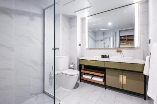 a bathroom with a toilet and a sink and a mirror at Powerhouse Hotel Tamworth by Rydges in Tamworth