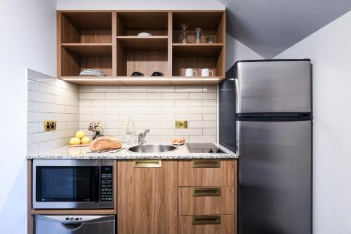 a kitchen with a stainless steel refrigerator and a sink at Powerhouse Hotel Tamworth by Rydges in Tamworth
