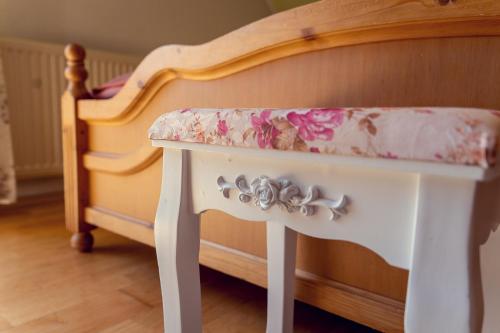 a white table with a floral seat next to a crib at Stangl - Hof in Bad Aussee