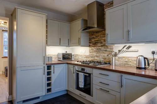 eine Küche mit weißen Schränken und Arbeitsflächen aus Holz in der Unterkunft Cosy 2 bed home CHESTERFIELD in Chesterfield