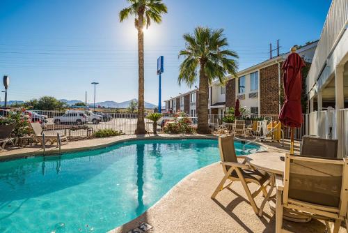 a swimming pool with chairs and a table and palm trees at Motel 6 Tucson, AZ - North in Tucson