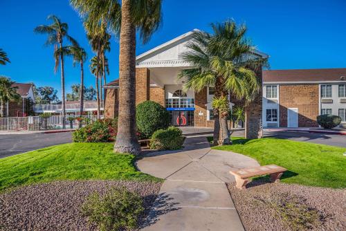 a bench in front of a building with palm trees at Motel 6 Tucson, AZ - North in Tucson