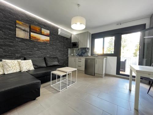 a living room with a black couch and a kitchen at Apartamentos Villa Serali Parking Gratis in Ronda