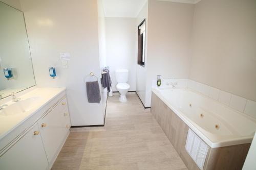 a white bathroom with a tub and a toilet at Palm City Motor Inn in Napier