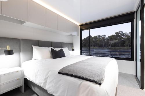 a bedroom with a large white bed and a large window at All Seasons Houseboats in Mildura