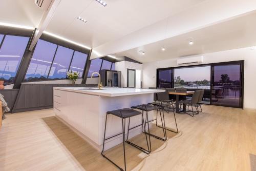 a kitchen with a counter and some chairs and windows at All Seasons Houseboats in Mildura