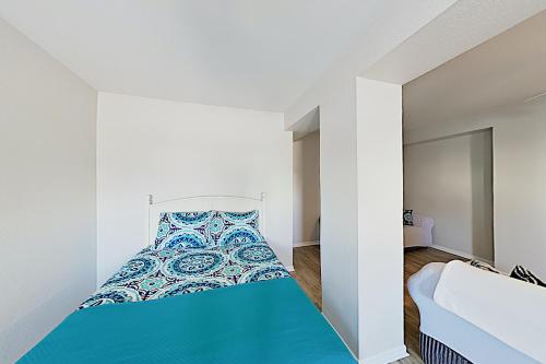 ein Schlafzimmer mit einem blauen Bett in einem weißen Zimmer in der Unterkunft Lost Colony Shiny Shell Cottage in Port Aransas