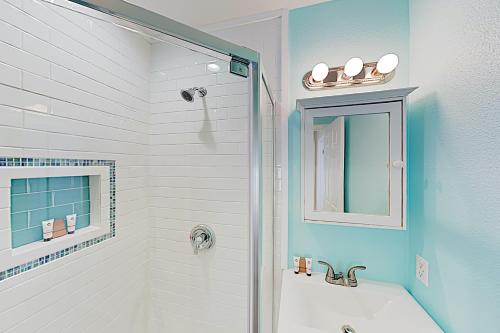 ein Bad mit einer Badewanne und einer Dusche mit einem Spiegel in der Unterkunft Lost Colony Shiny Shell Cottage in Port Aransas