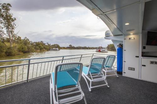 three chairs on the deck of a boat on a river at All Seasons Houseboats in Mildura
