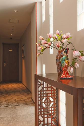 a vase with flowers on a table in a hallway at CHERRY BOUTIQUE HOTEL in Ho Chi Minh City