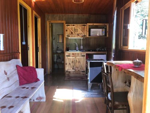 a kitchen with wooden cabinets and a table in a room at Recanto Baú - Chalé in Bom Jardim da Serra