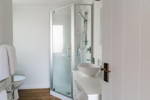 La salle de bains est pourvue d'une douche et d'un lavabo. dans l'établissement Te Puna Cottage Gardens B&B, à Tauranga