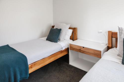 2 Einzelbetten in einem Zimmer mit weißen Wänden in der Unterkunft Te Puna Cottage Gardens B&B in Tauranga