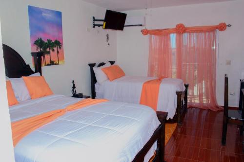 a bedroom with two beds with orange and white sheets at Three Kings Hotel in Vertières