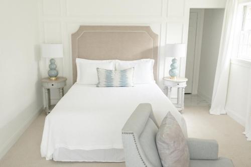 a white bedroom with a white bed and a chair at Fairville Inn in Chadds Ford