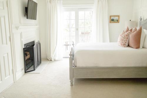 a white bedroom with a bed and a fireplace at Fairville Inn in Chadds Ford