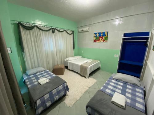 duas camas em um quarto com paredes verdes em Kitnet Praia do Trapiche em Penha