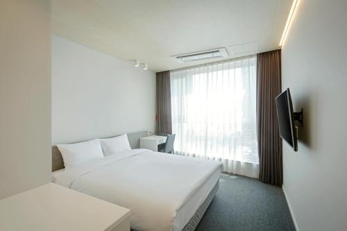 a hotel room with a white bed and a window at Grand City Hotel Changwon in Changwon
