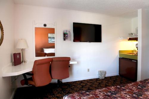 a hotel room with a desk and a television at Granada Inn in Santa Clara