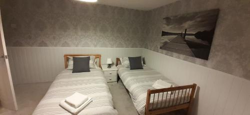 2 camas individuais num quarto com uma fotografia na parede em Ladbury House in Walsall, Near the M6 and near Walsall Manor Hospital, with free parking and easy access to Birmingham city centre, perfect for contractors and families, only 20 minutes from NEC and Birmingham airport em Bescot