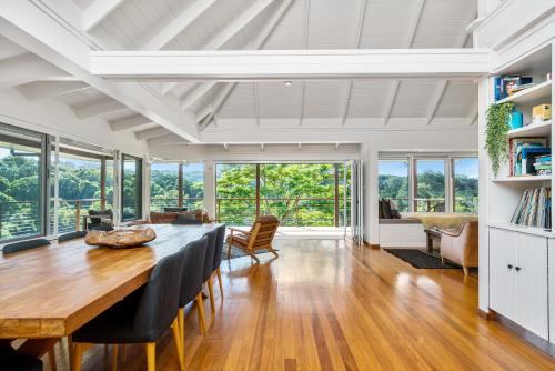a dining room with a table and chairs and windows at Coorabell Estate in Coorabell Creek