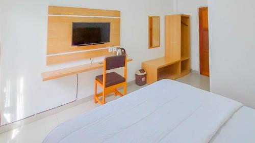 a bedroom with a bed and a desk with a tv at Urbanview Hotel Bundaran Besar Palangkaraya by RedDoorz in Palangkaraya